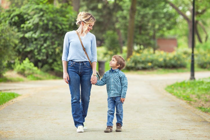 Young mother and her cute little son walking in a park