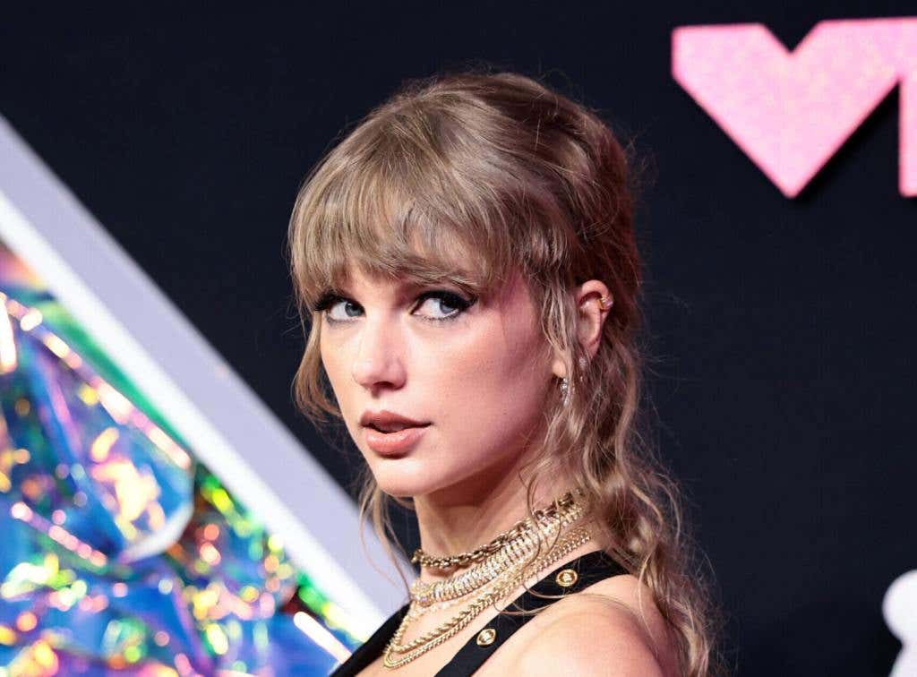 Taylor Swift attends the 2023 MTV Video Music Awards facing left looking right wearing a black dress.