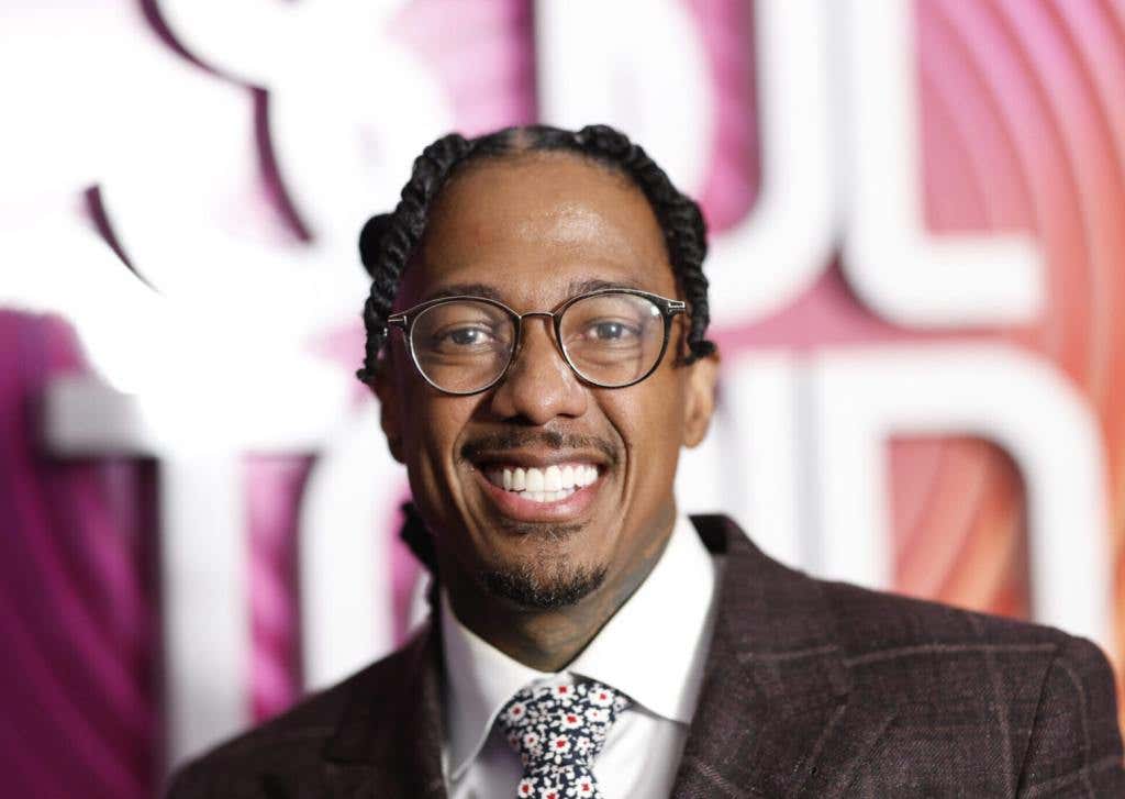 Nick Cannon attends the 2023 BET Soul Train Awards smiling wearing a leather blazer and tie.