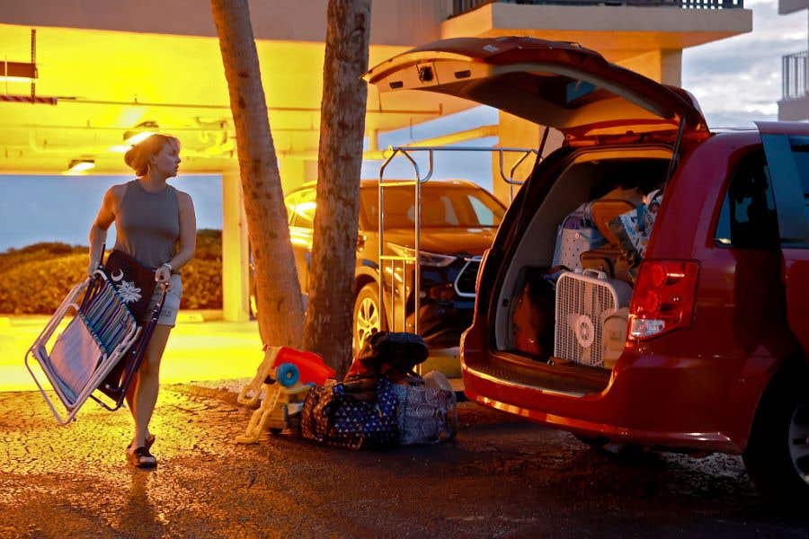 Woman putting items in a car trunk as