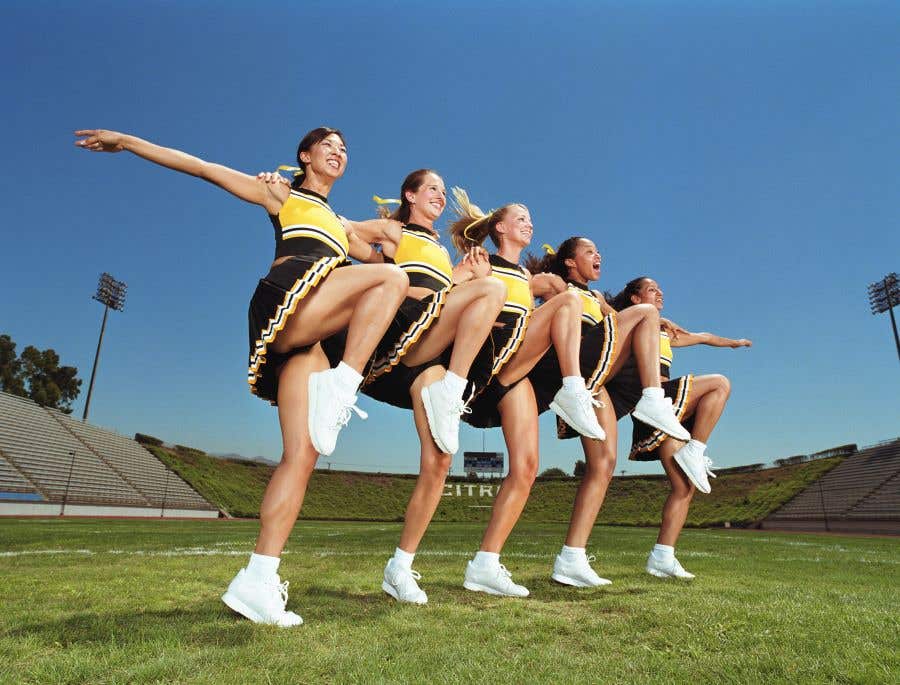 Line of Cheerleaders with arms around each others shoulders and knees up to kick for big game weekend events in SWFL