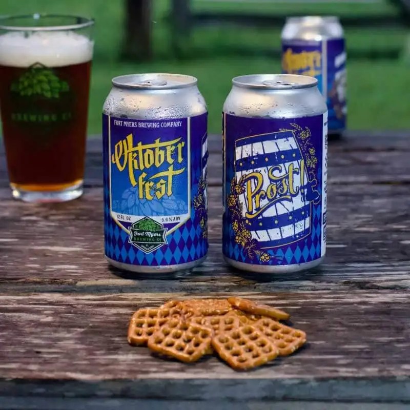 Two cans of beer, two glasses of beer and a stack of pretzels on a table outdoors for things to do this weekend