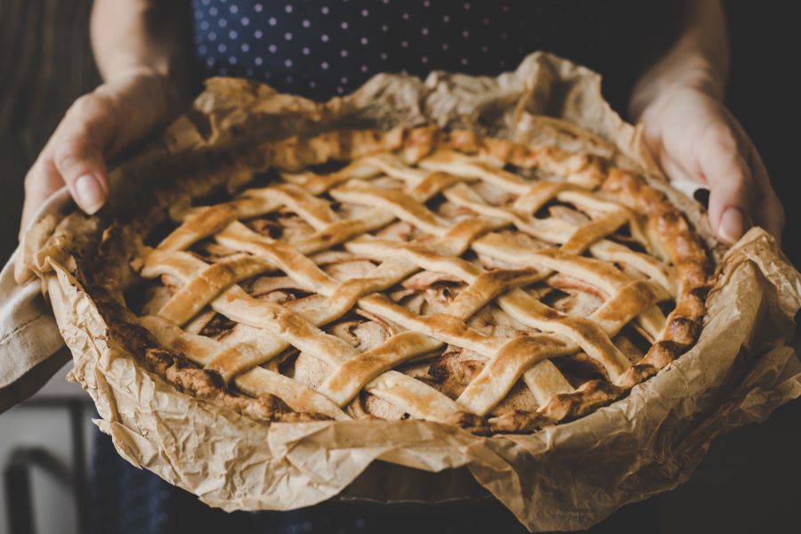 Hands holding homemade delicious apple pie. Close up.