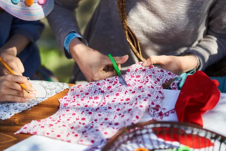 Hands cutting a red and white cloth for DIY Christmas decorations